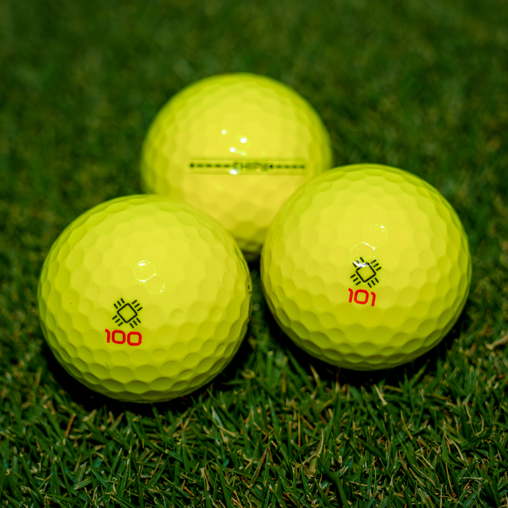Three yellow CHIP’d smart golf balls on a putting green