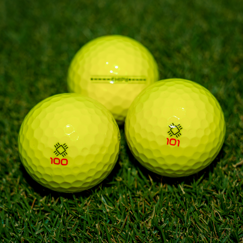 Three yellow CHIP’d smart golf balls on a putting green